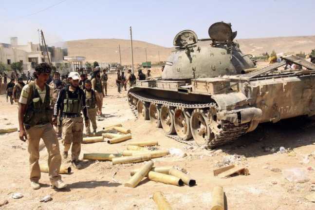 Free Syrian Army fighters inspect munitions and a tank that belonged to forces loyal to Syria's President Bashar al-Assad after they seized Aleppo's town of Khanasir