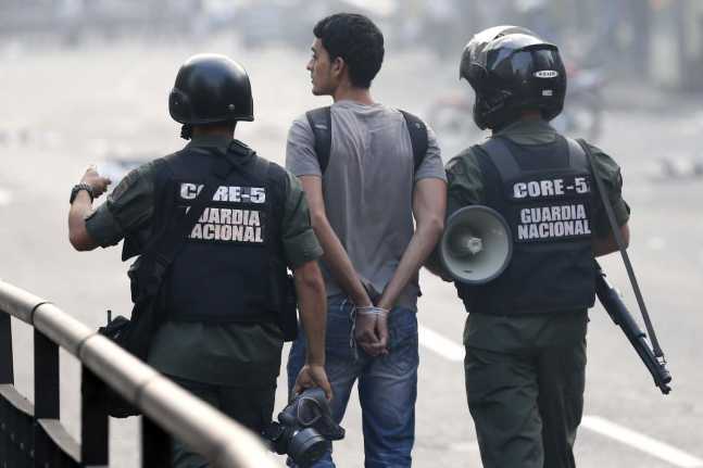 National guards walk with a detained man after the riots in Caracas
