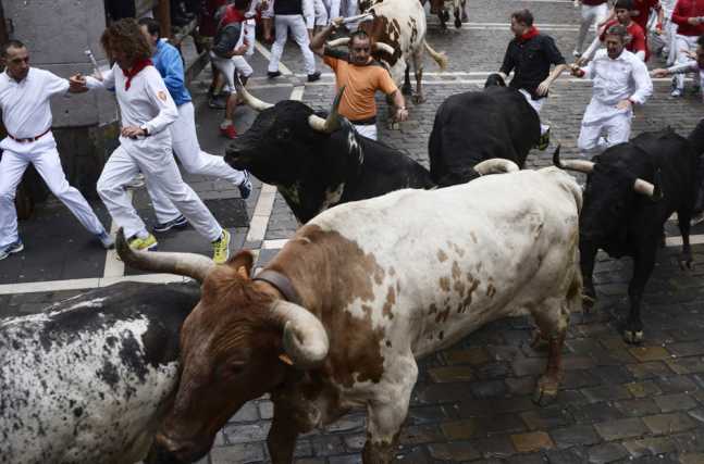 Runners sprint alongside Torrestrella fighting bulls at the Estafeta corner during the first running of the bulls of the San Fermin festival in Pamplona