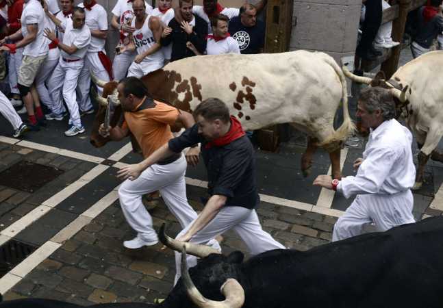 Runners sprint alongside Torrestrella fighting bulls at the Estafeta corner during the first running of the bulls of the San Fermin festival in Pamplona