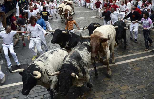 Runners sprint alongside Torrestrella fighting bulls at the Estafeta corner during the first running of the bulls of the San Fermin festival in Pamplona