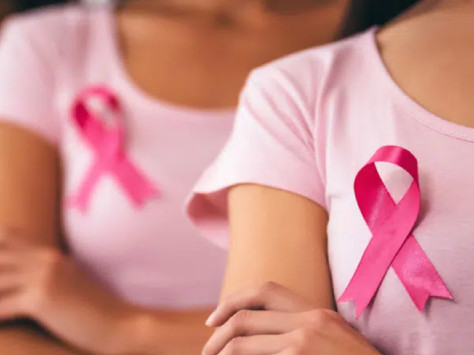 mujeres usando un lazo rosa, símbolo de la lucha contra el cáncer de mama